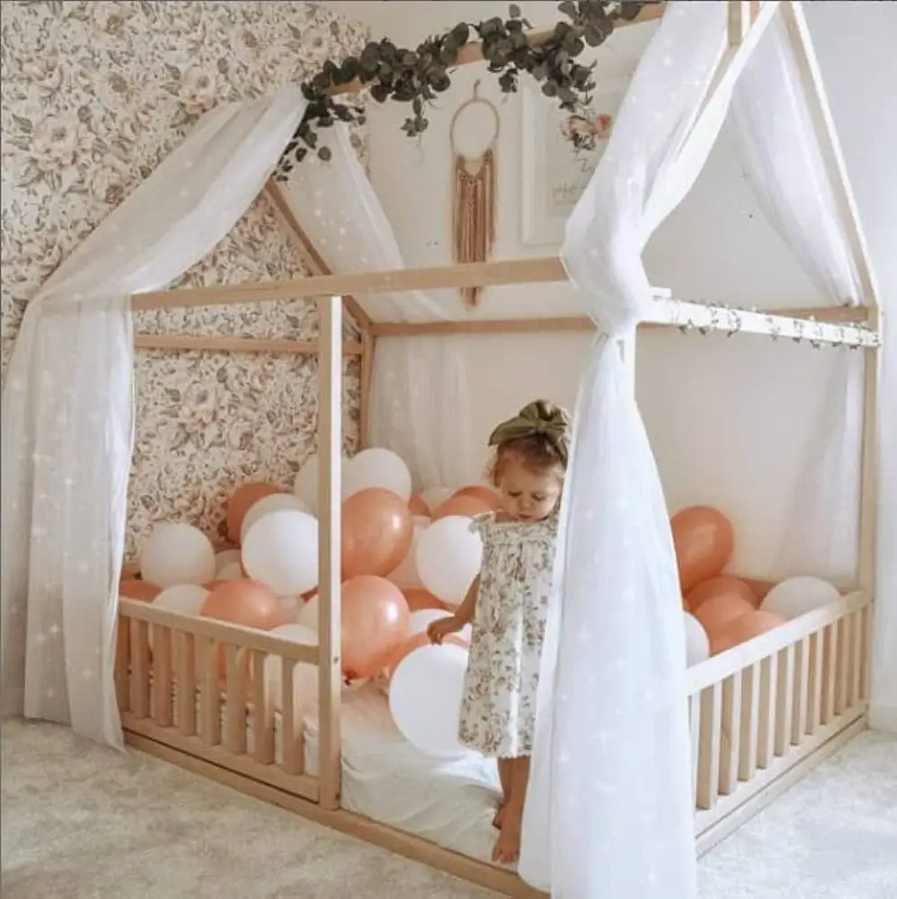 little girl playing in a montessori bed with balloons